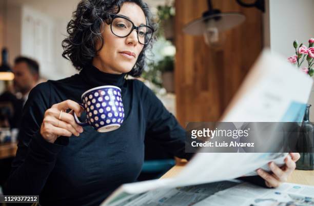 businesswoman at cafe reading newspaper - reading imagens e fotografias de stock
