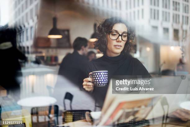 female business professional reading a newspaper in cafe - mass media foto e immagini stock