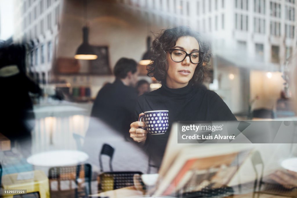 Female business professional reading a newspaper in cafe