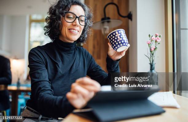 woman at cafe using digital tablet at coffee shop - reading glasses imagens e fotografias de stock