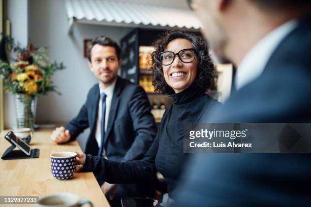 group of three business people sitting at a coffee shop - corporate business photos et images de collection