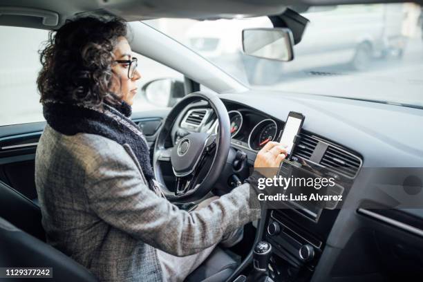 woman uses navigation on her mobile phone in the car - coat drive stock pictures, royalty-free photos & images