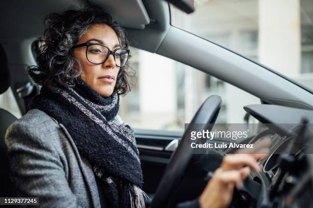 woman behind the wheel using phone for navigation - female driving stock-fotos und bilder