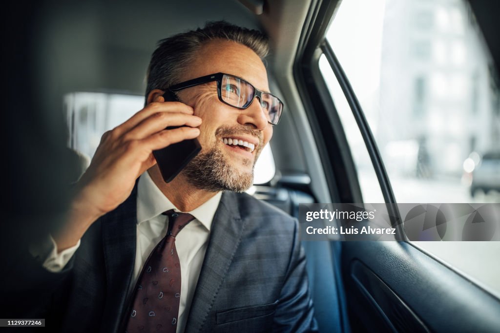 Entrepreneur using phone while traveling by a car
