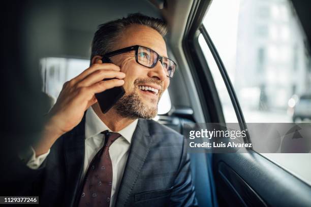 entrepreneur using phone while traveling by a car - photo call stock-fotos und bilder