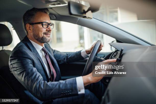 businessman searching location phone while driving a car - autista mestiere foto e immagini stock