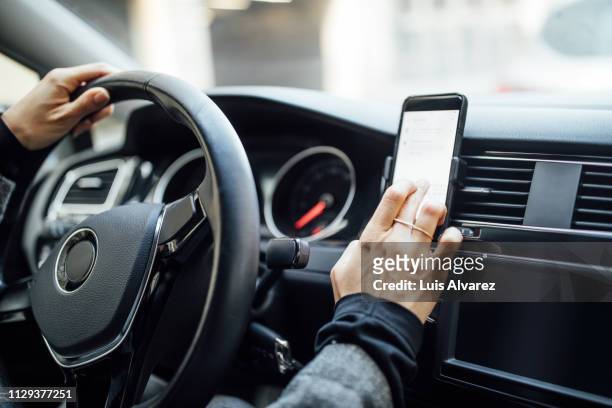 woman using phone while driving a car - auto navigation stock-fotos und bilder
