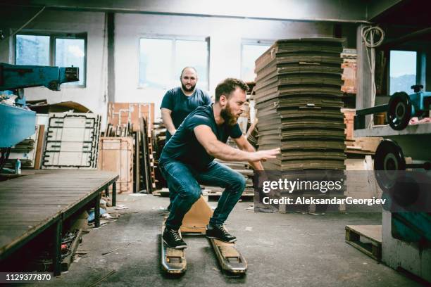 male workers in cardboard factory playing with transportation cart - work fun stock pictures, royalty-free photos & images