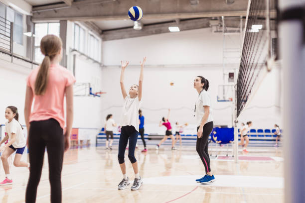 female volleyball team exercising indoors - girls volleyball stock pictures, royalty-free photos & images