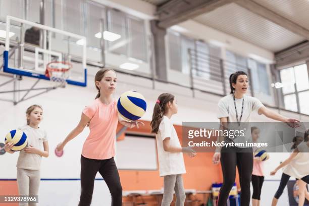 vrouwelijke coach praten met meisjes op volleybalveld - zaalvolleybal stockfoto's en -beelden