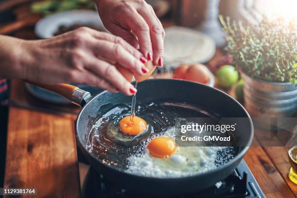 freír el huevo en una cacerola cocinar en cocina doméstica - fritura fotografías e imágenes de stock