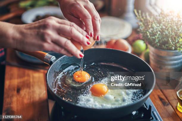 freír el huevo en una cacerola cocinar en cocina doméstica - sartenes fotografías e imágenes de stock