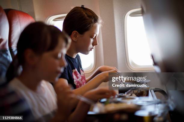 sisters having airplane food - plane food stock pictures, royalty-free photos & images