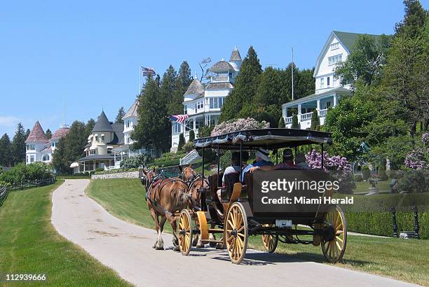 Horse-drawn carriage passes by the mansions overlooking Lake Huron on West Bluff Road, at Mackinac Island, Michigan.