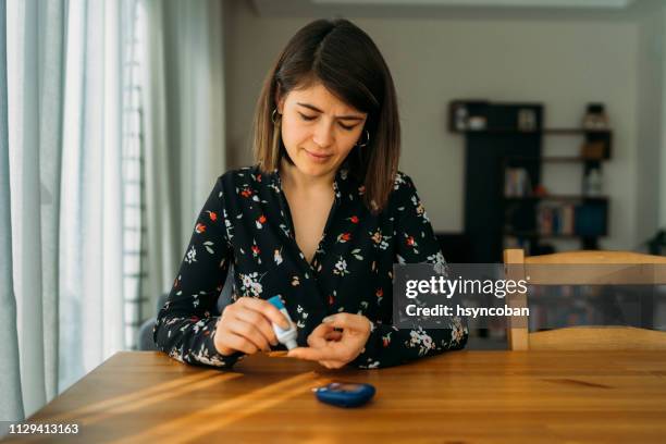 young woman measuring blood sugar level - blood sugar test stock pictures, royalty-free photos & images