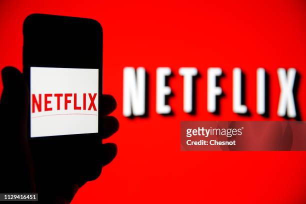 In this photo iIllustration, the Netflix logo is seen on the screen of an iPhone in front of a computer screen showing a Netflix logo on February 13,...