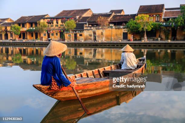 vietnamese women paddling in old town in hoi an city, vietnam - vietnam imagens e fotografias de stock