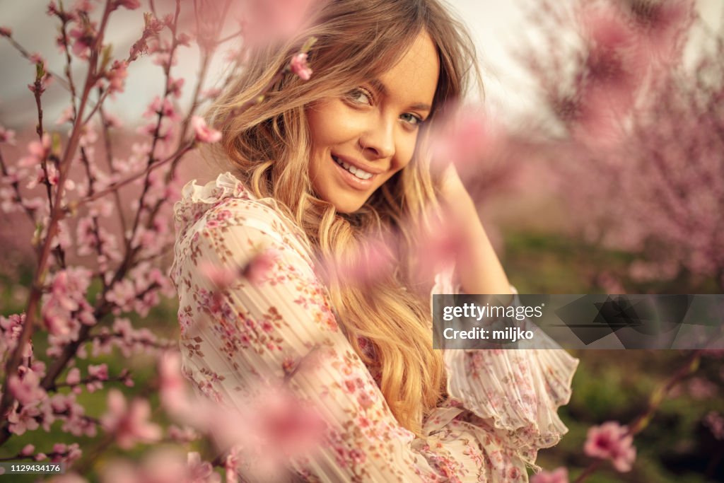 Amazing young woman posing in apricot tree orchard at spring