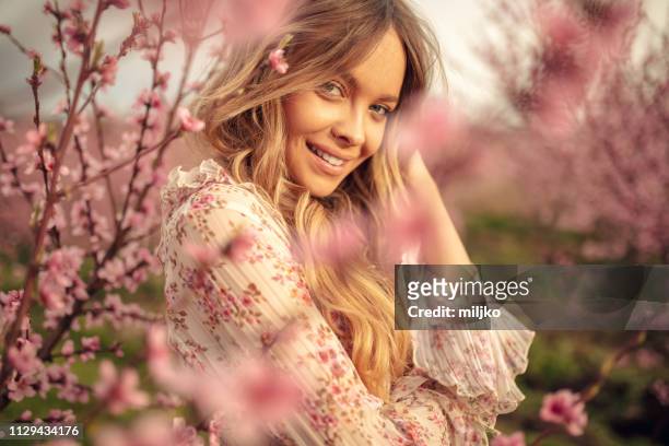 amazing young woman posing in apricot tree orchard at spring - fashion stock pictures, royalty-free photos & images