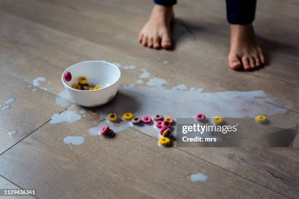 spilled bowl of milk and cereal - kids feet in home stock-fotos und bilder