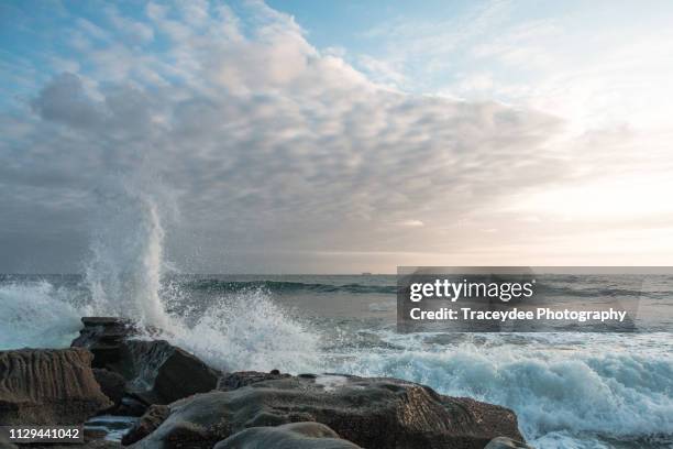 white clouds with waves crashing on a rock formation at moffat beach, queensland - spray foam stock pictures, royalty-free photos & images