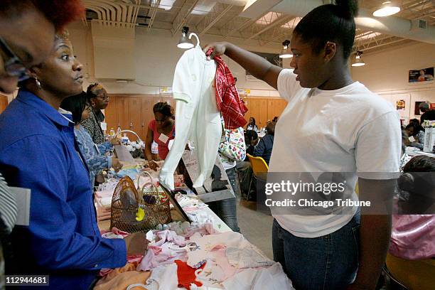 Simpson Academy student Tierra Coleman looks over baby clothes while attending a 'baby shower' at the school, on Saturday, October 13 in Chicago,...