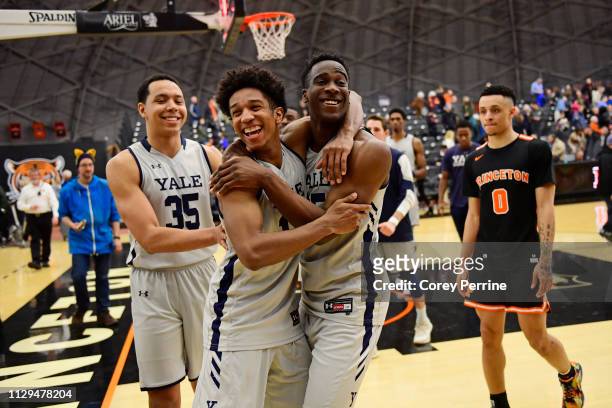 Trey Phills and Miye Oni of the Yale Bulldogs hug, reacting to the win, as teammate Isaiah Kelly and Jaelin Llewellyn of the Princeton Tigers look on...