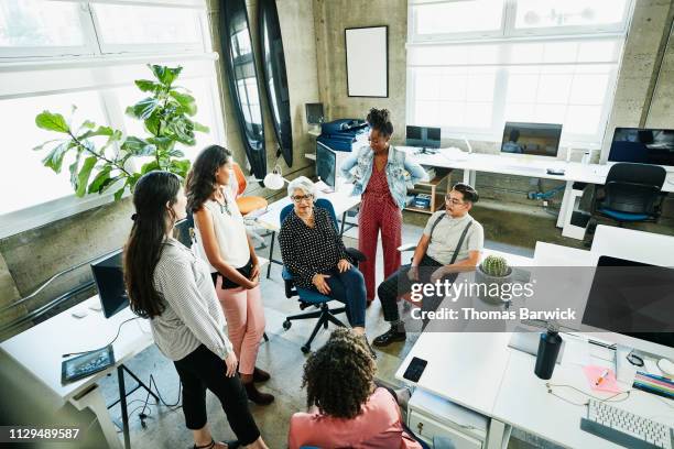 mature female business owner leading meeting with employees in design studio - person of colour - fotografias e filmes do acervo