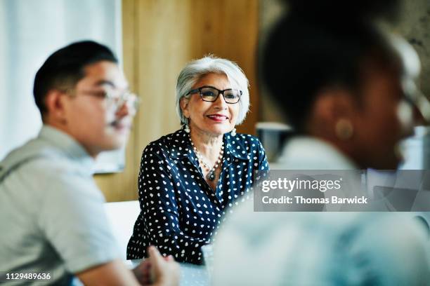 Smiling mature female business owner listening during presentation during meeting in office conference room