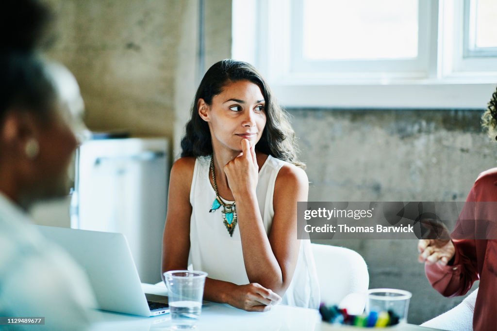 Smiling businesswoman listening to coworker during meeting in conference room