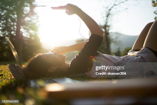 asian female student happy moment and laydown on the green grass listen music from mobilephone - studierendenvertretung stock-fotos und bilder