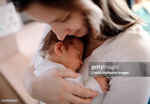 a close-up of a mother holding a newborn baby son at home. - mother sleeping child stock-fotos und bilder