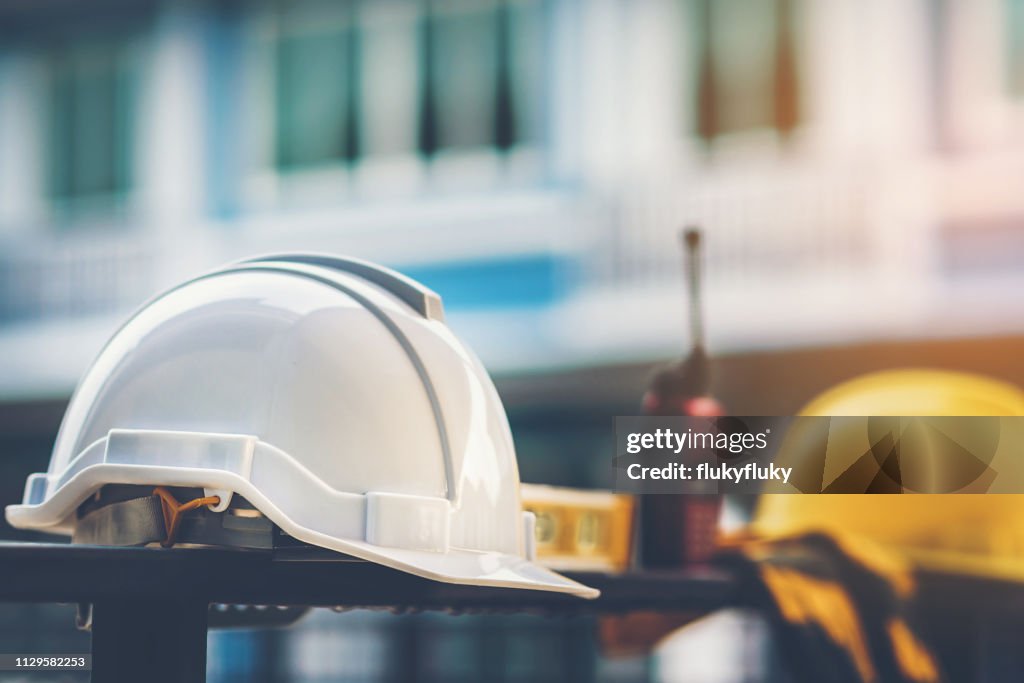 White and yellow helmet with construction water,gloves and radio that are placed on steel house fence.
