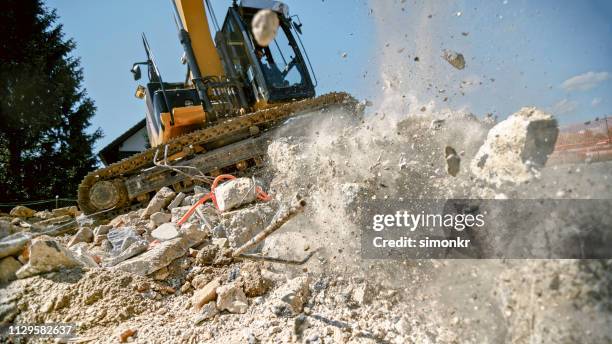 escavatore afferra blocco di calcestruzzo frantumante in aria - detriti foto e immagini stock