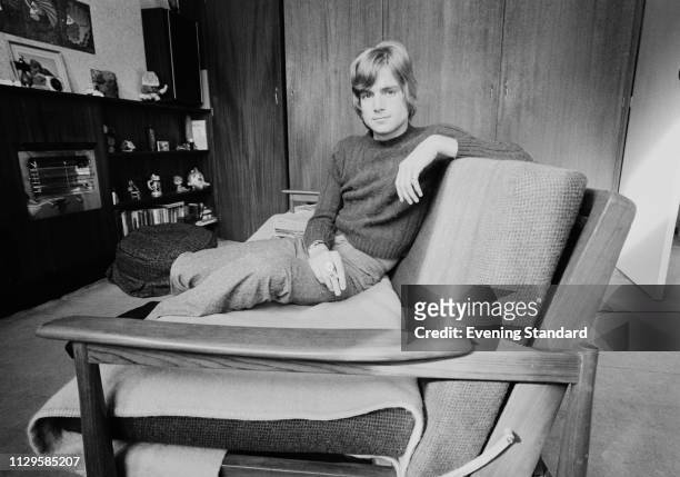 English musician Justin Hayward of rock band The Moody Blues smoking a cigarette while sitting on a couch, UK, 7th November 1968.