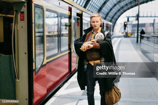 single mother checking the time while boarding train - baby bag bildbanksfoton och bilder