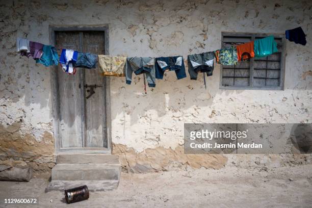 poor village house in africa with clothesline - omgeven stockfoto's en -beelden