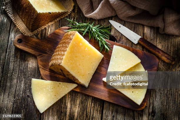 spanish food: manchego cheese on rustic wooden table - cheeses imagens e fotografias de stock