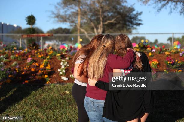 Two sisters hug their mother while looking on at a memorial setup for those killed at Marjory Stoneman Douglas High School on February 14, 2019 in...