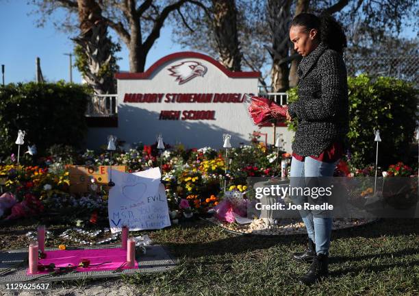 Sheena Billups prepares to lay flowers in a memorial setup at Marjory Stoneman Douglas High School for those killed during a mass shooting on...