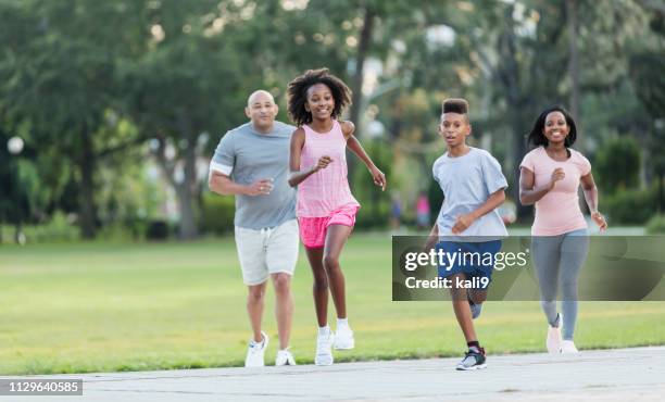 interracial family running in park together - race 8 stock pictures, royalty-free photos & images