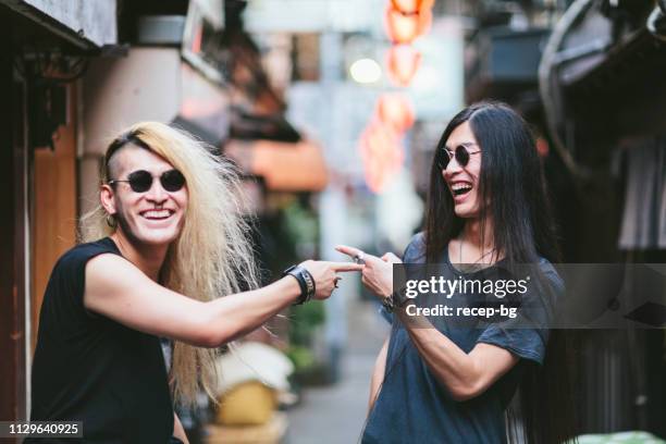 two men laughing to each other in small alley - asian twins stock pictures, royalty-free photos & images