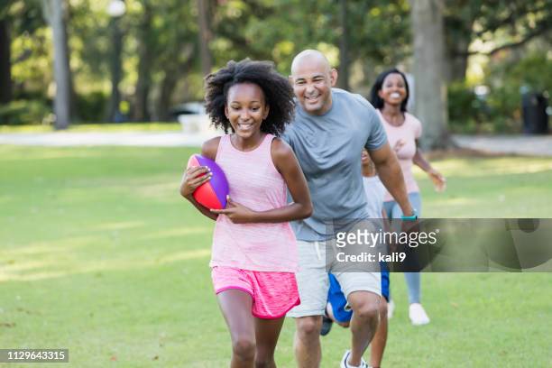 interracial family with two children having fun in park - american football play stock pictures, royalty-free photos & images