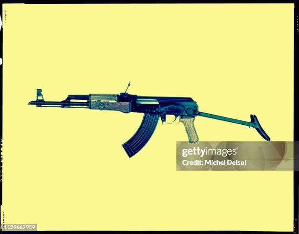 Left profile of an AKM assault rifle with an attached magazine, seen against a yellow background, New York, New York, March 9, 1994. The photo was...