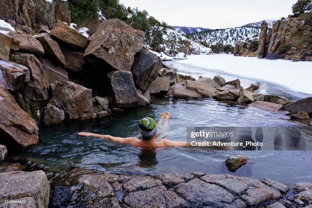 Uomo che si gode l'immersione rilassante nelle sorgenti termali naturali in inverno lungo il fiume Colorado