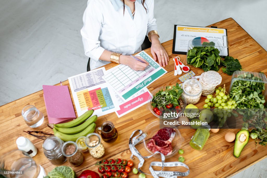 Schreiben eine Diät-Plan auf dem Tisch voll von gesunden Lebensmitteln