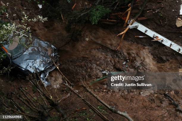 Water flows by a car that was swept down a hill by a mudslide during a rain storm on February 14, 2019 in Sausalito, California. 50 homes in the town...