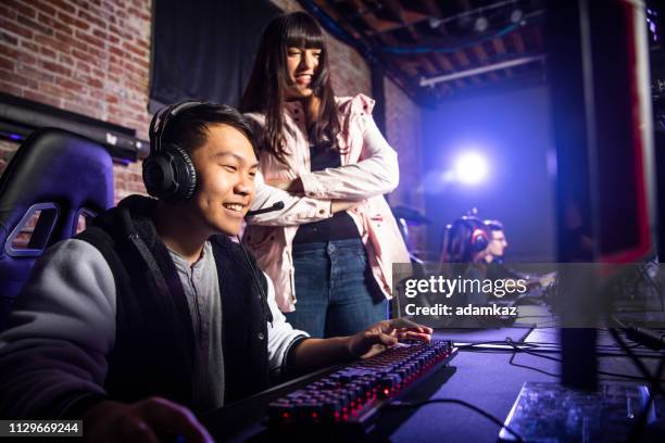 young woman coaching a man playing esports - boss over shoulder stock pictures, royalty-free photos & images