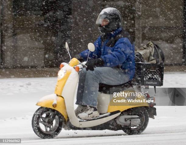 Motorist makes his way through downtown Wichita, Kansas, on a moped during a heavy snowstorm on Saturday, January 20 in Wichita, Kansas.