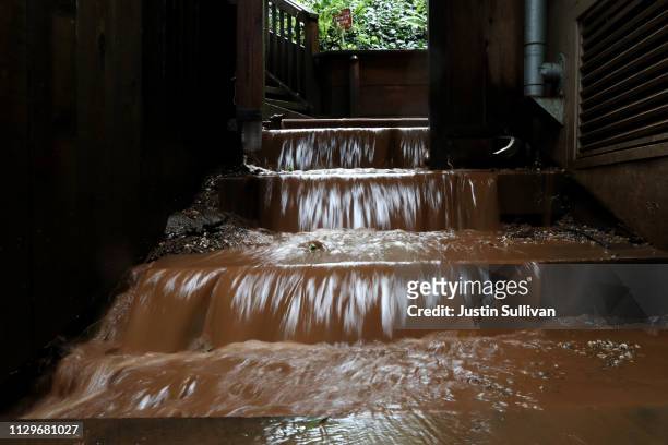 Muddy water flows down the stairs of a home near where a mudslide swept away a home during a rain storm on February 14, 2019 in Sausalito,...